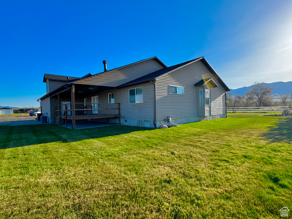 Back of property with a mountain view, a yard, and fence
