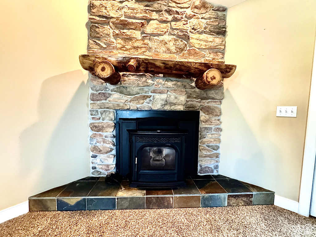 Room details with a wood stove, carpet, and baseboards