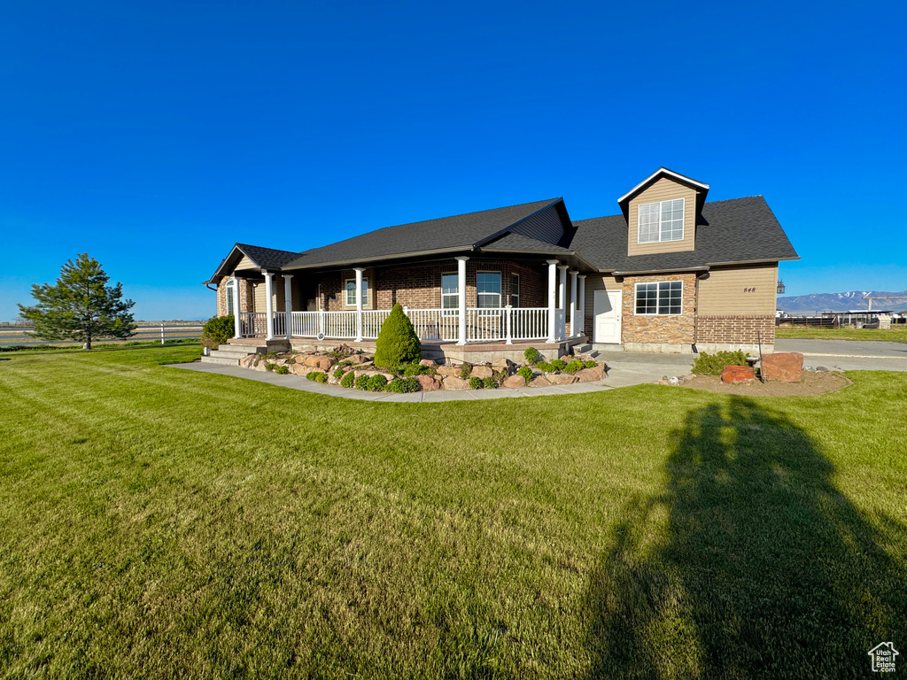 View of front of home featuring a front lawn, brick siding, and covered porch