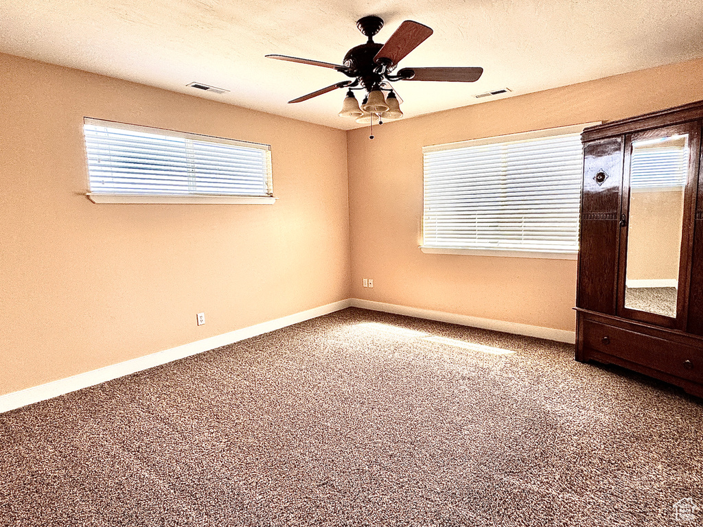 Empty room featuring ceiling fan, baseboards, and visible vents