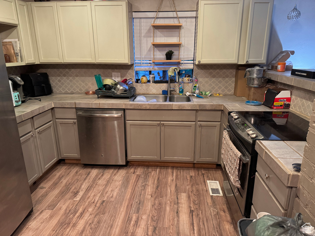 Kitchen with open shelves, a sink, electric stove, and dishwasher