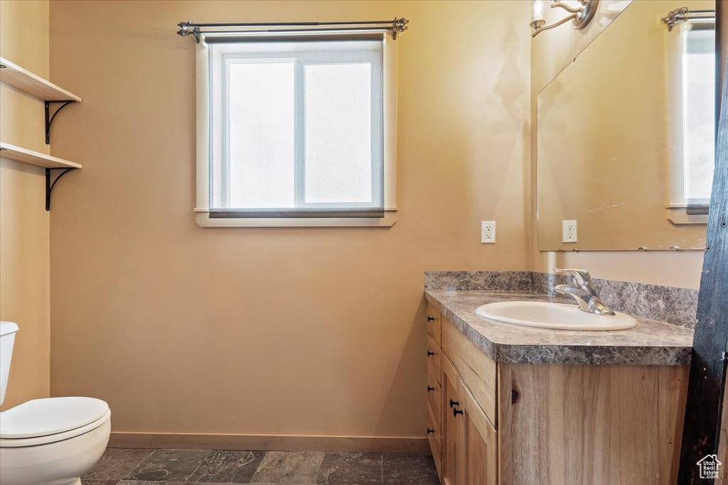 Bathroom with toilet, baseboards, and plenty of natural light