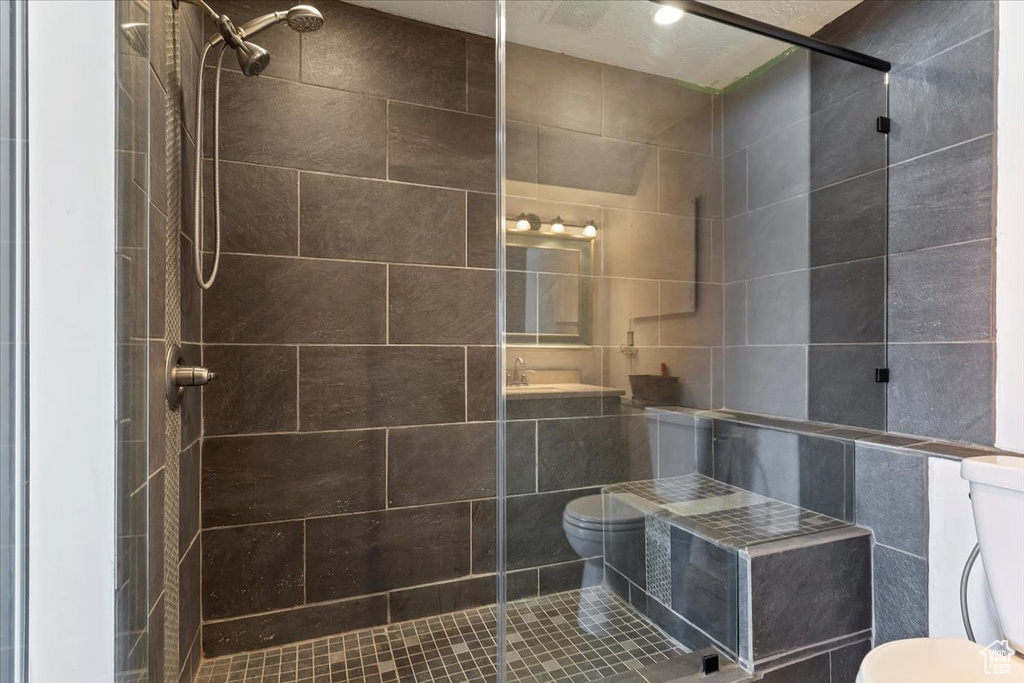 Bathroom with toilet, tile walls, and a shower stall