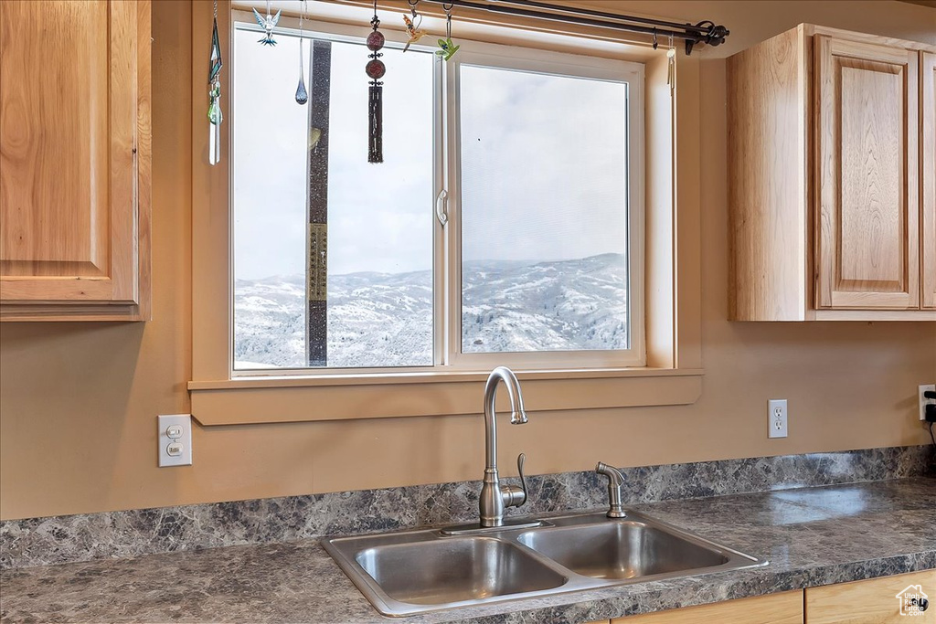 Kitchen with dark countertops, light brown cabinetry, and a sink