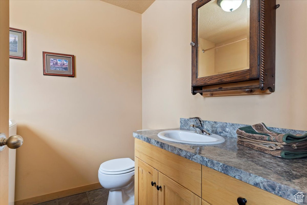 Half bathroom featuring toilet, baseboards, and vanity