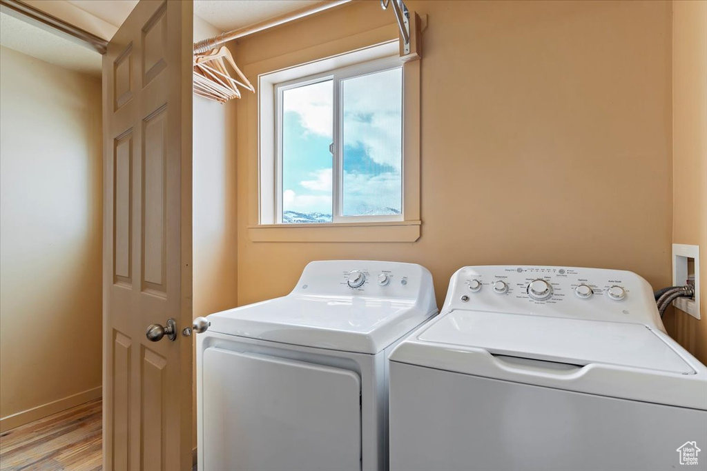 Washroom featuring independent washer and dryer, light wood-style floors, baseboards, and laundry area