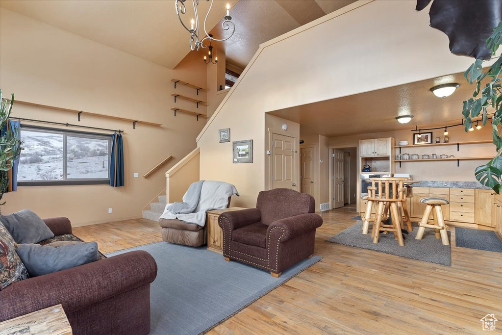 Living room featuring a towering ceiling, light wood-type flooring, visible vents, stairway, and baseboards