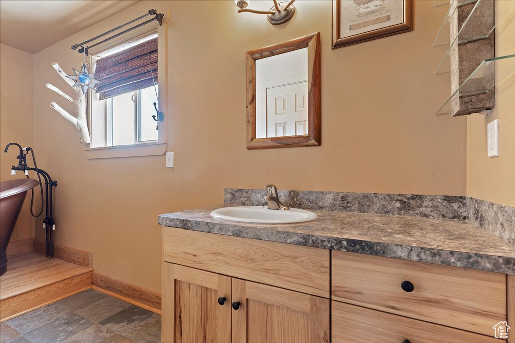 Bathroom featuring baseboards, vanity, and a freestanding tub