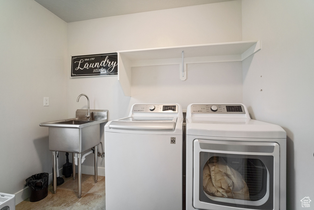 Clothes washing area featuring laundry area, washer and clothes dryer, baseboards, and a sink