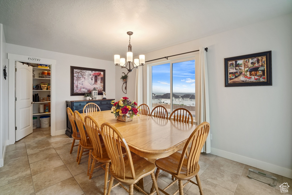 Dining area with light tile patterned flooring, baseboards, and a notable chandelier