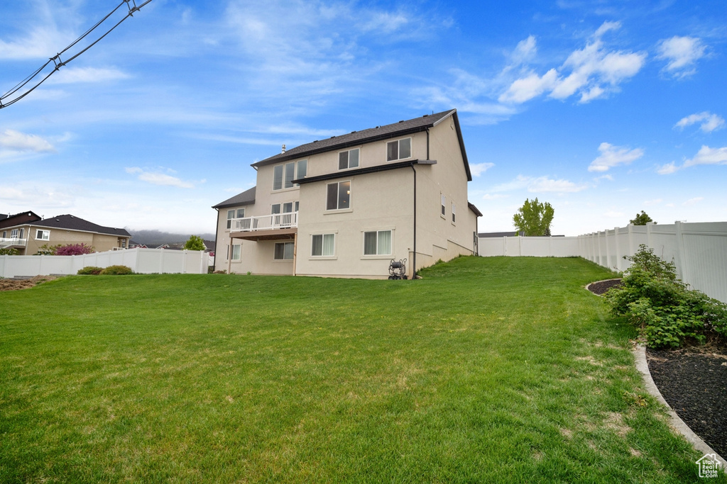 Back of house with a fenced backyard, stucco siding, and a lawn