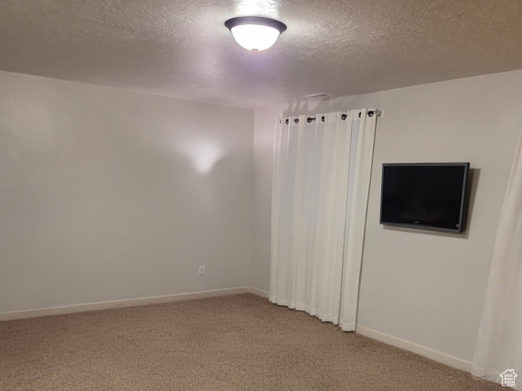 Unfurnished room featuring carpet floors, a textured ceiling, and baseboards