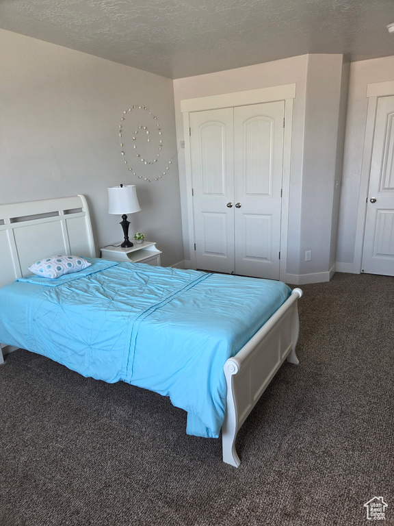 Bedroom with carpet, a closet, baseboards, and a textured ceiling