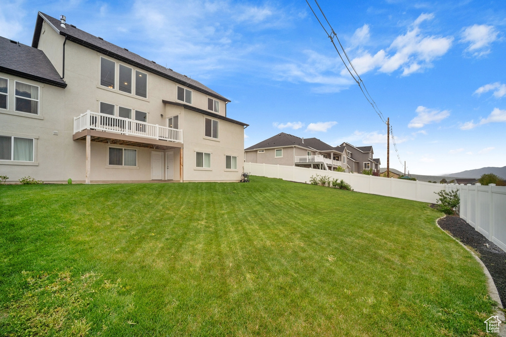 Rear view of house featuring a fenced backyard, stucco siding, and a yard
