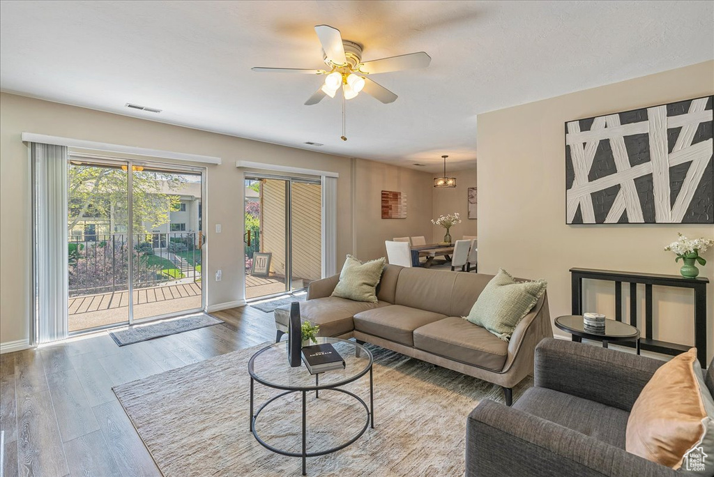 Living room with baseboards, ceiling fan, visible vents, and wood finished floors