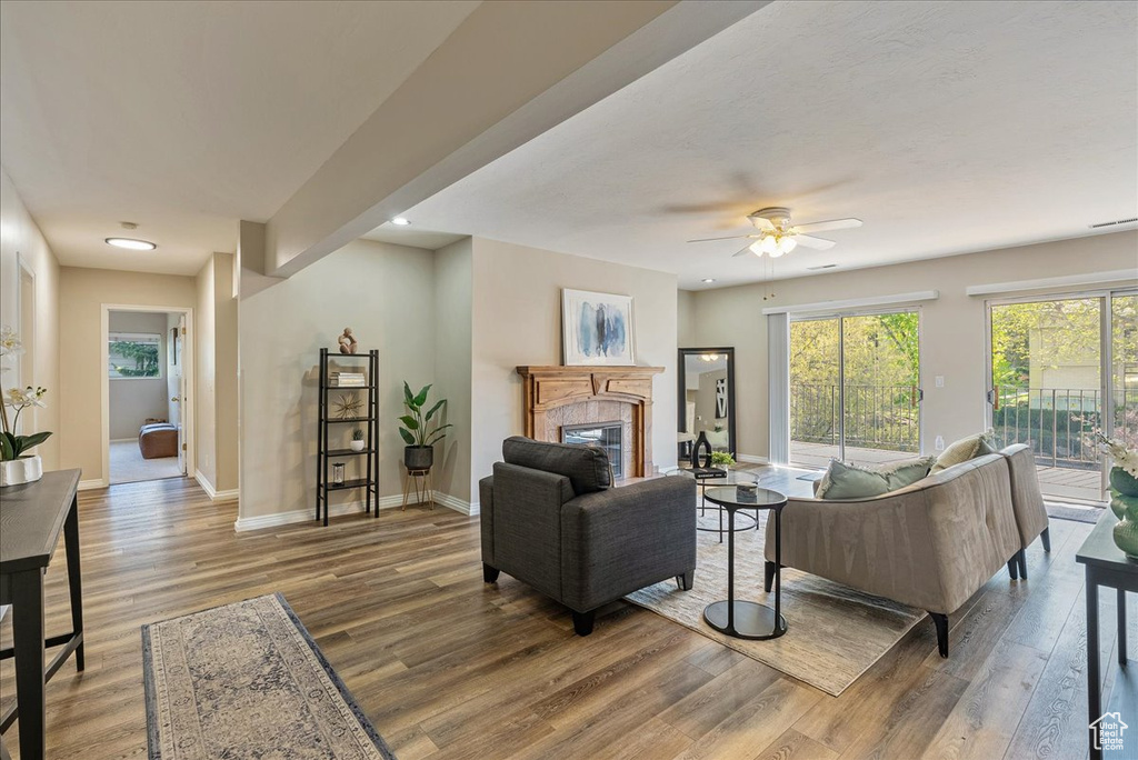 Living area featuring recessed lighting, baseboards, a glass covered fireplace, ceiling fan, and wood finished floors