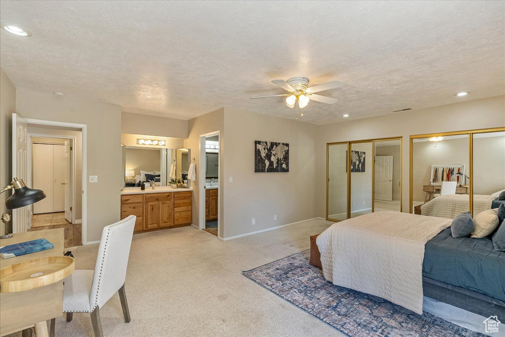 Bedroom featuring light colored carpet, a textured ceiling, two closets, and recessed lighting