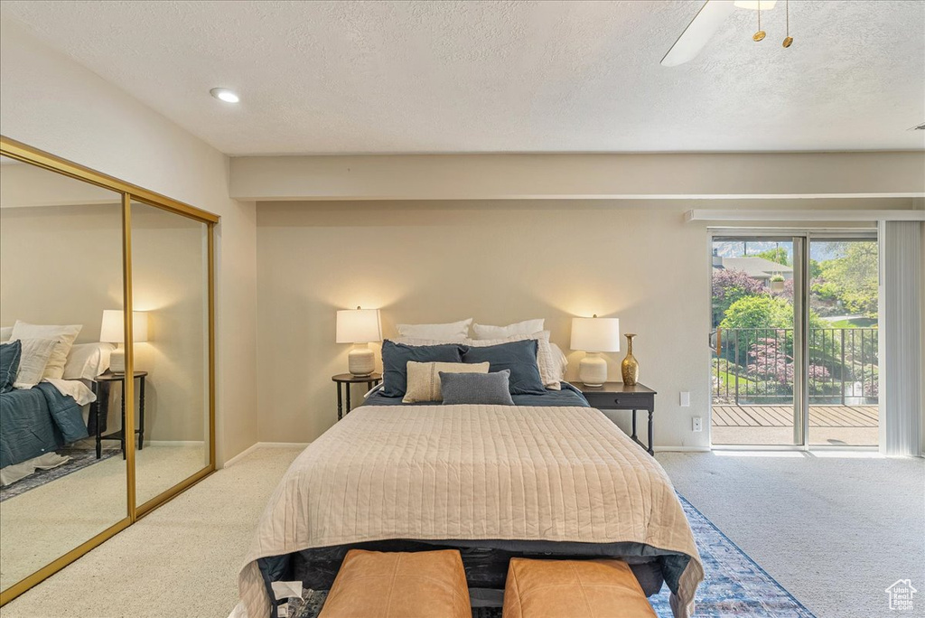 Carpeted bedroom with a ceiling fan, a closet, a textured ceiling, and access to exterior