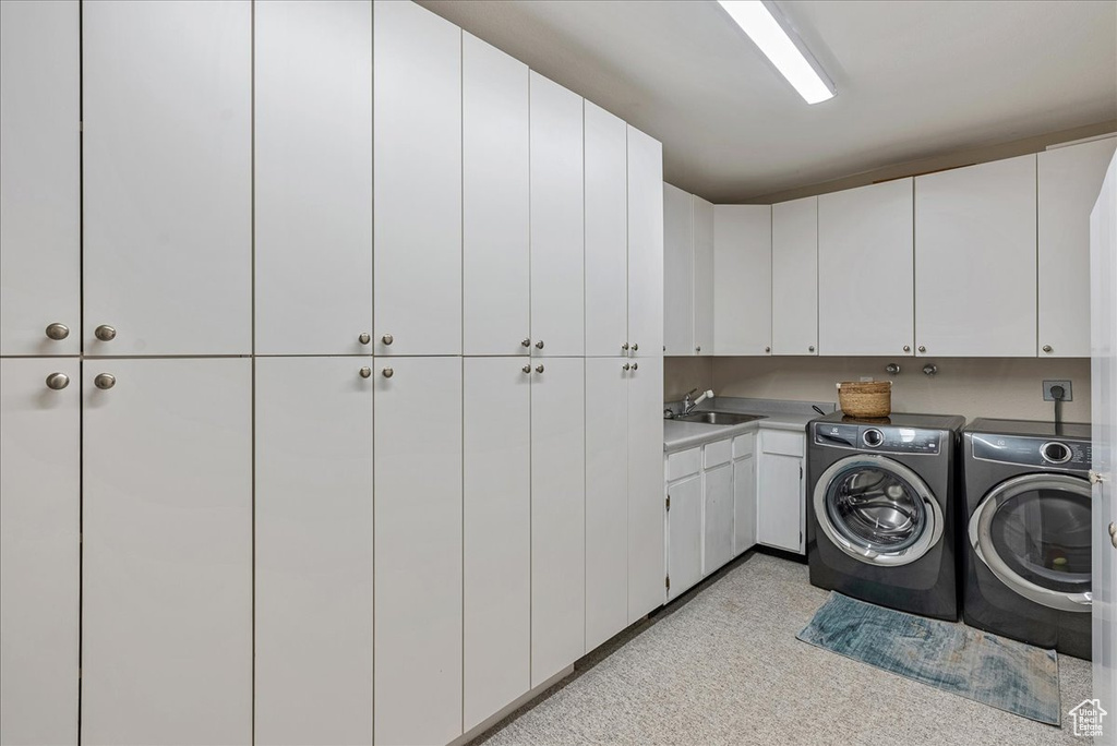 Laundry area with a sink, cabinet space, and washer and clothes dryer