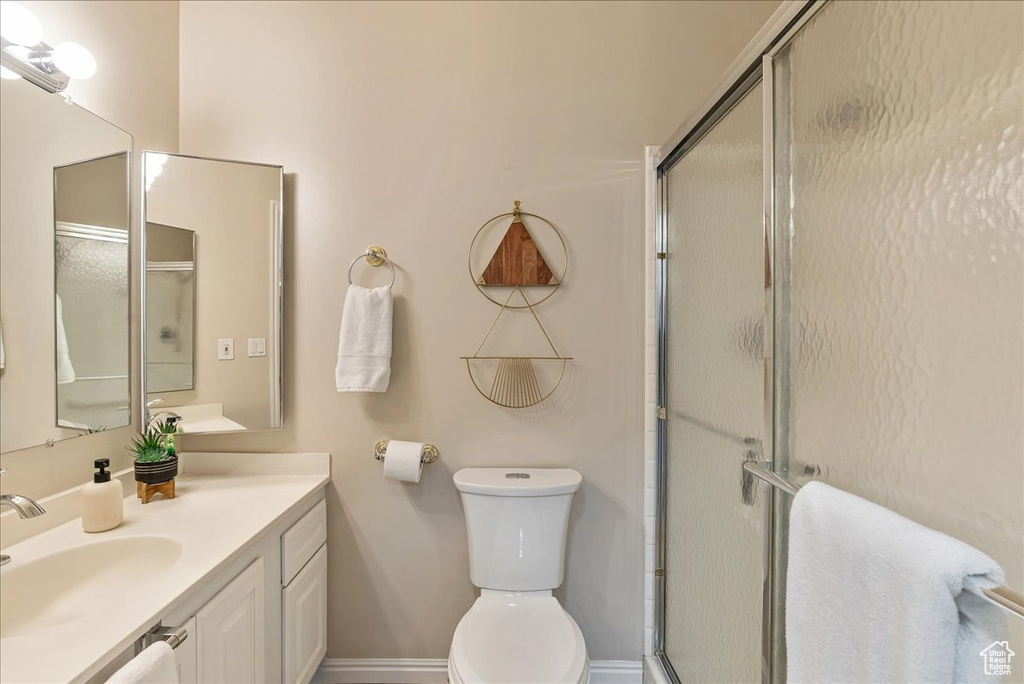 Bathroom with a shower stall, baseboards, vanity, and toilet