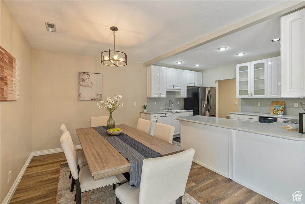 Dining space featuring wood finished floors, baseboards, visible vents, recessed lighting, and a notable chandelier