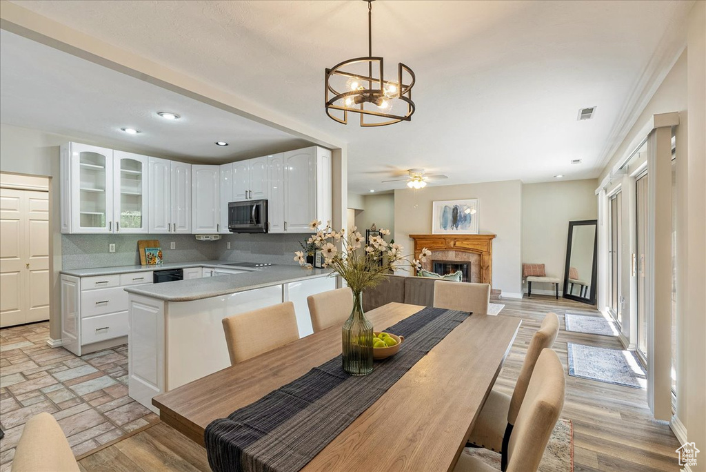 Kitchen with stainless steel microwave, a peninsula, a fireplace, light countertops, and glass insert cabinets
