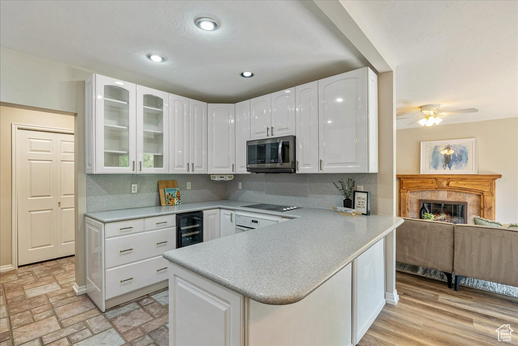 Kitchen featuring white cabinets, black electric cooktop, glass insert cabinets, and stainless steel microwave