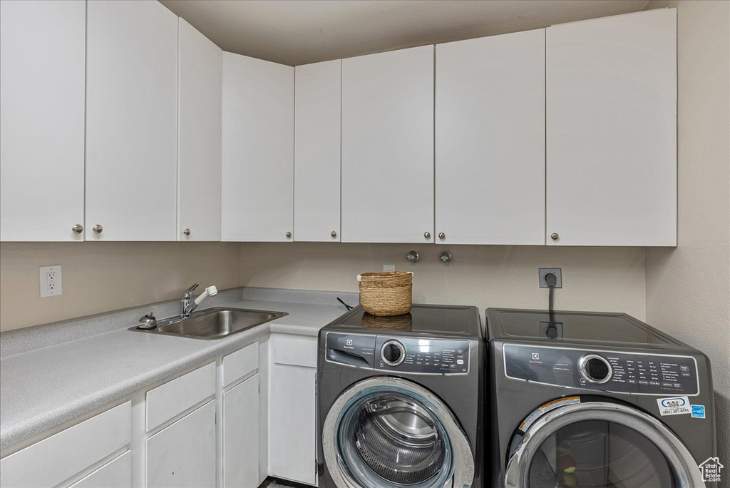 Laundry room with cabinet space, washing machine and clothes dryer, and a sink