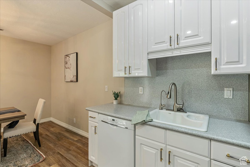 Kitchen with a sink, tasteful backsplash, dark wood-type flooring, dishwasher, and white cabinets