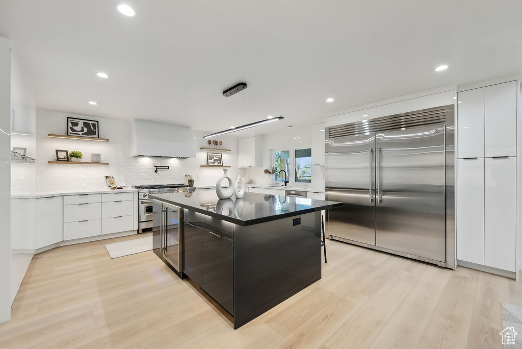 Kitchen with light wood-style flooring, premium appliances, modern cabinets, a sink, and white cabinetry