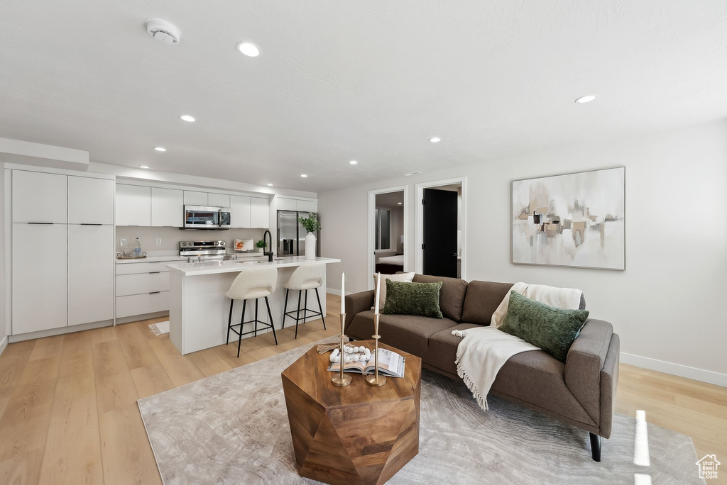 Living room with light wood-style floors, baseboards, and recessed lighting