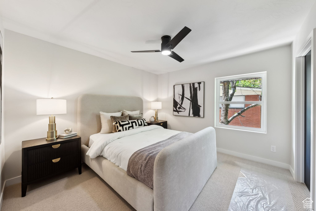 Bedroom featuring light colored carpet, baseboards, and ceiling fan