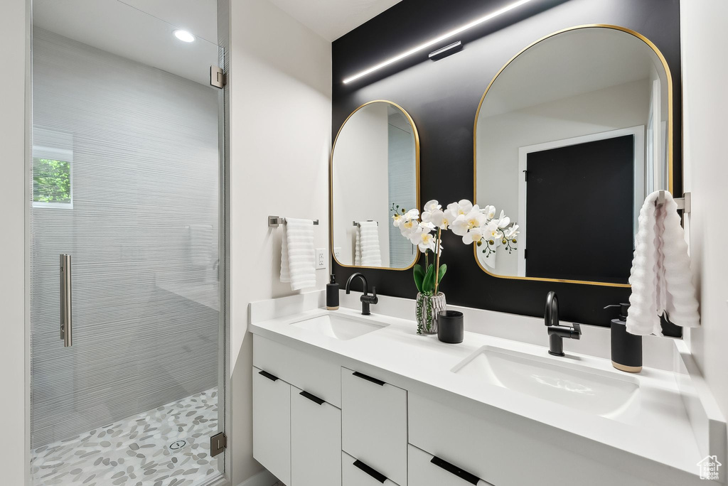 Bathroom featuring a stall shower, recessed lighting, double vanity, and a sink