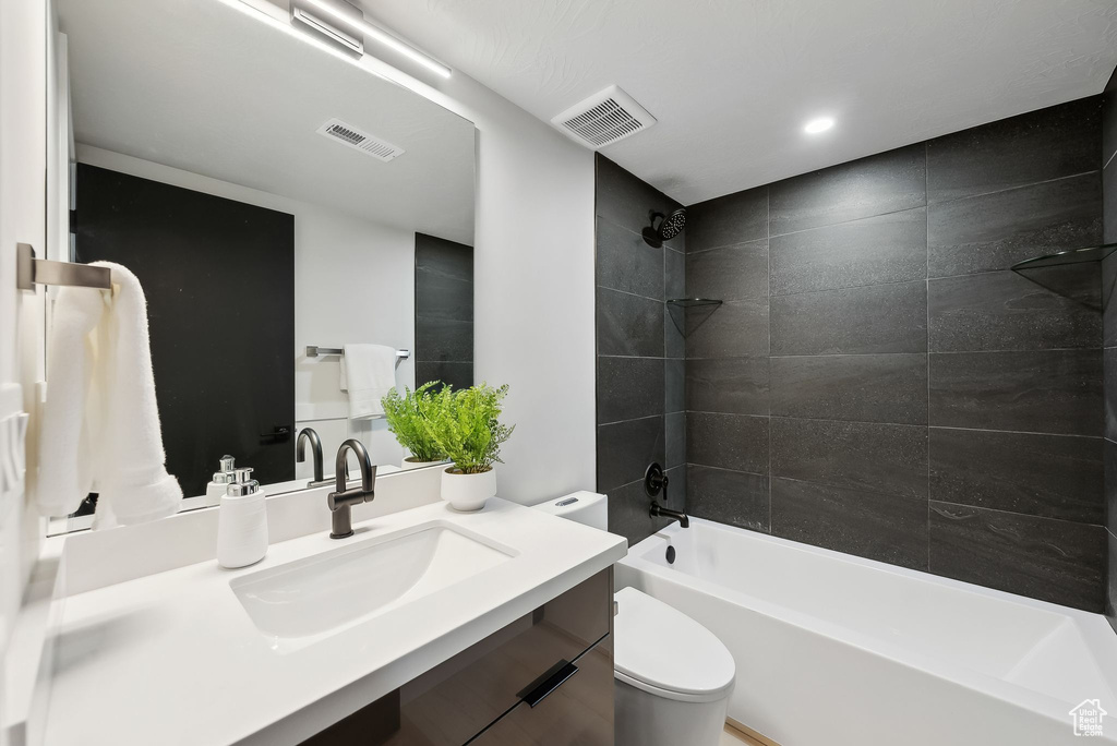 Bathroom featuring toilet, visible vents, vanity, and washtub / shower combination