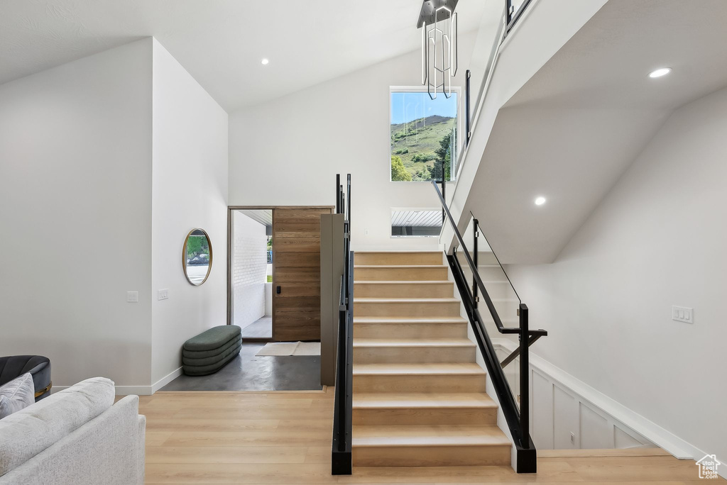 Stairs featuring baseboards, high vaulted ceiling, recessed lighting, and wood finished floors