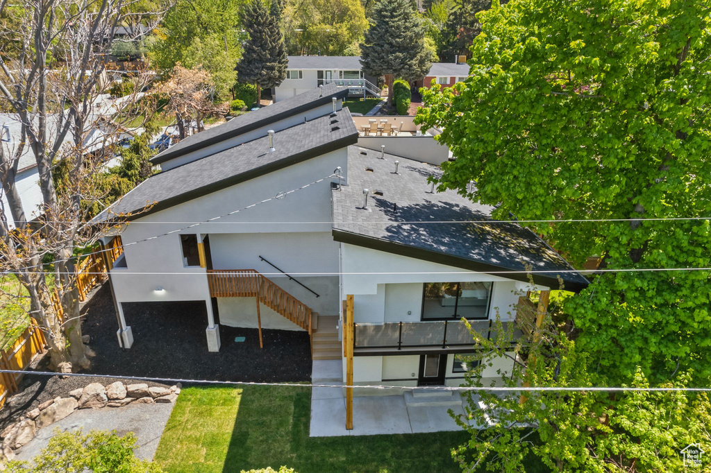 Rear view of house featuring stairway, a patio area, a shingled roof, and stucco siding