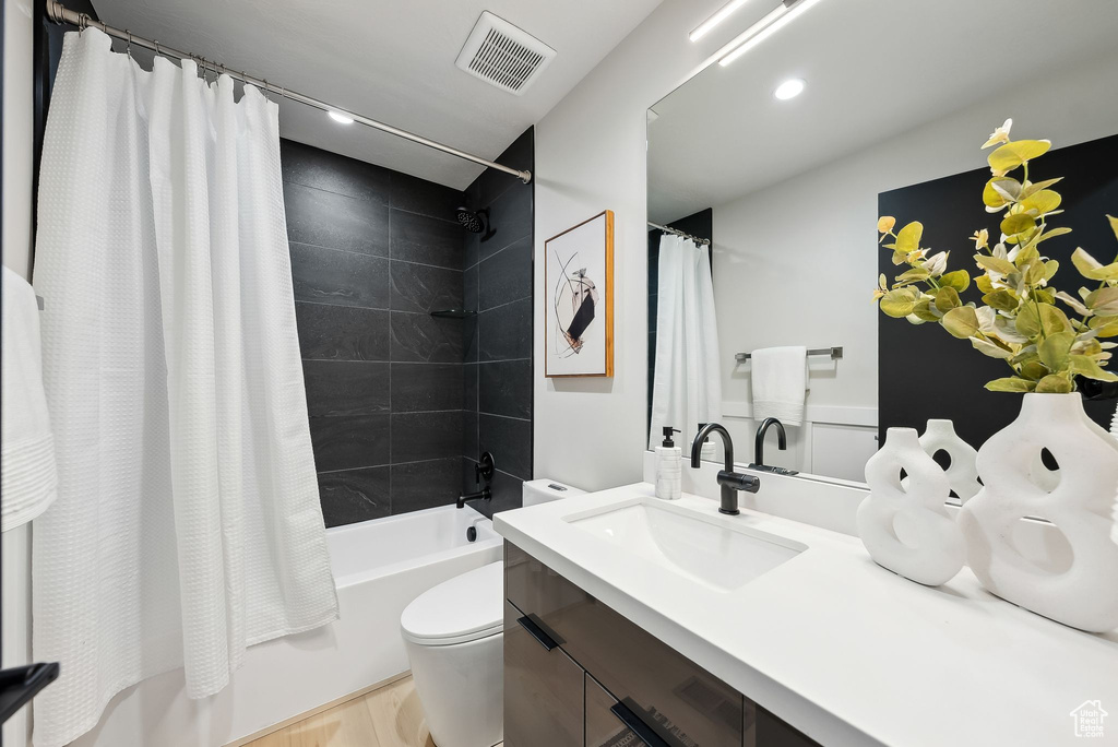 Full bath featuring shower / bath combo with shower curtain, toilet, visible vents, and vanity