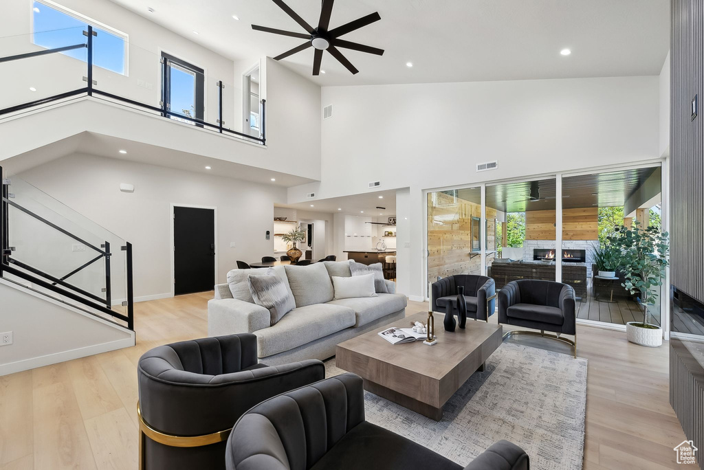 Living area featuring visible vents, light wood-style flooring, a ceiling fan, and a high ceiling