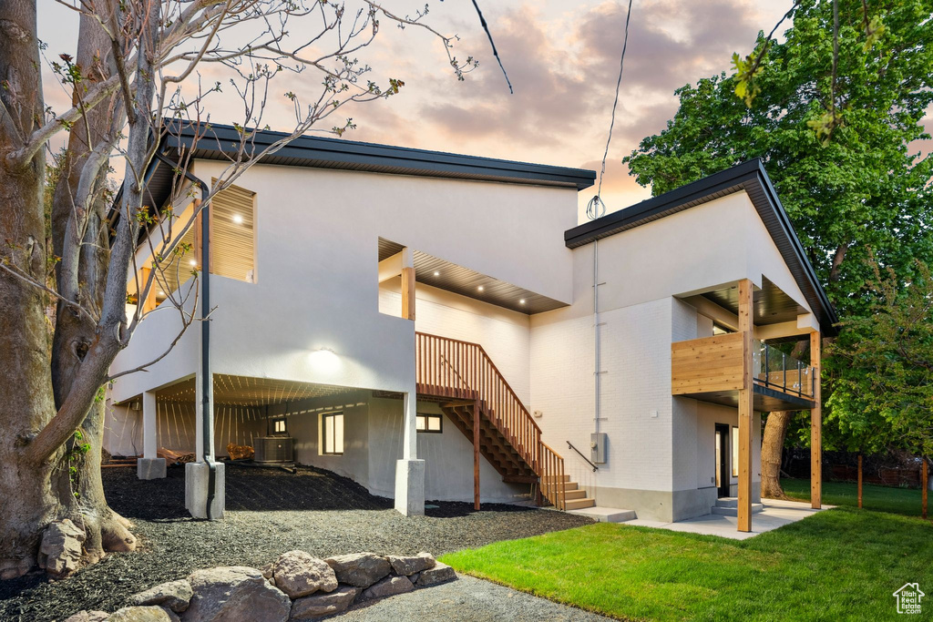 Back of house with a yard, a patio area, central AC unit, and stucco siding