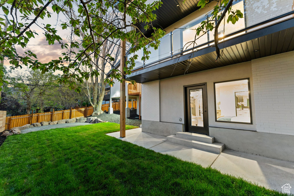 Exterior space featuring a patio area, fence, brick siding, and a lawn