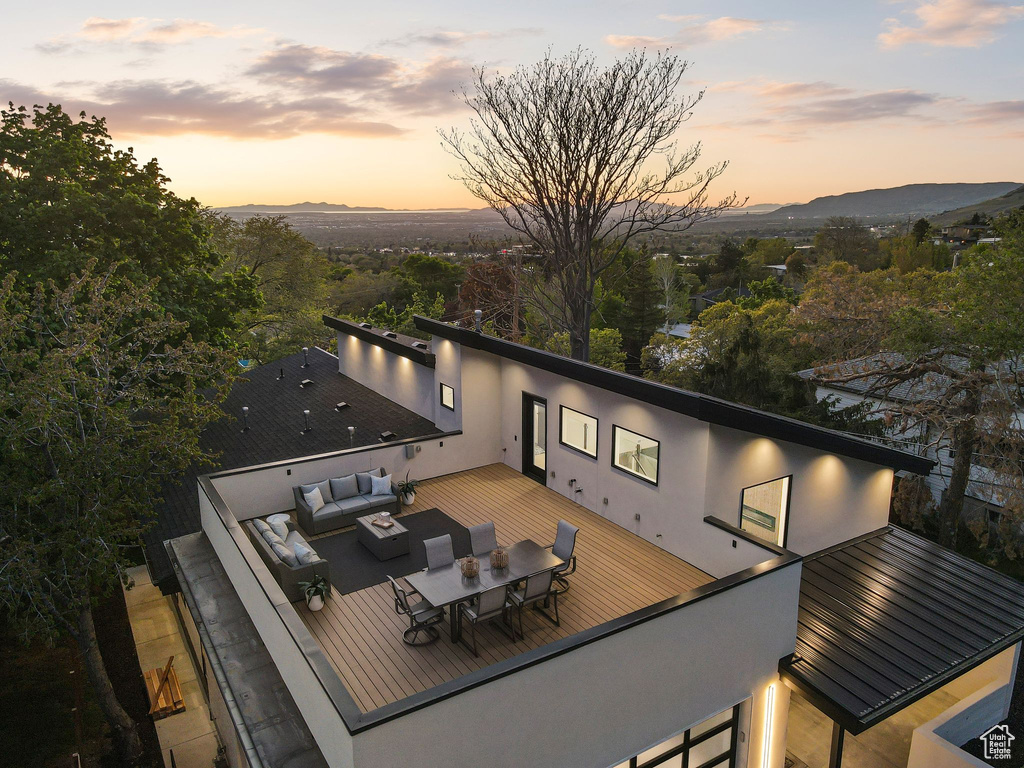Back of property with a deck with mountain view, outdoor dining space, stucco siding, and outdoor lounge area