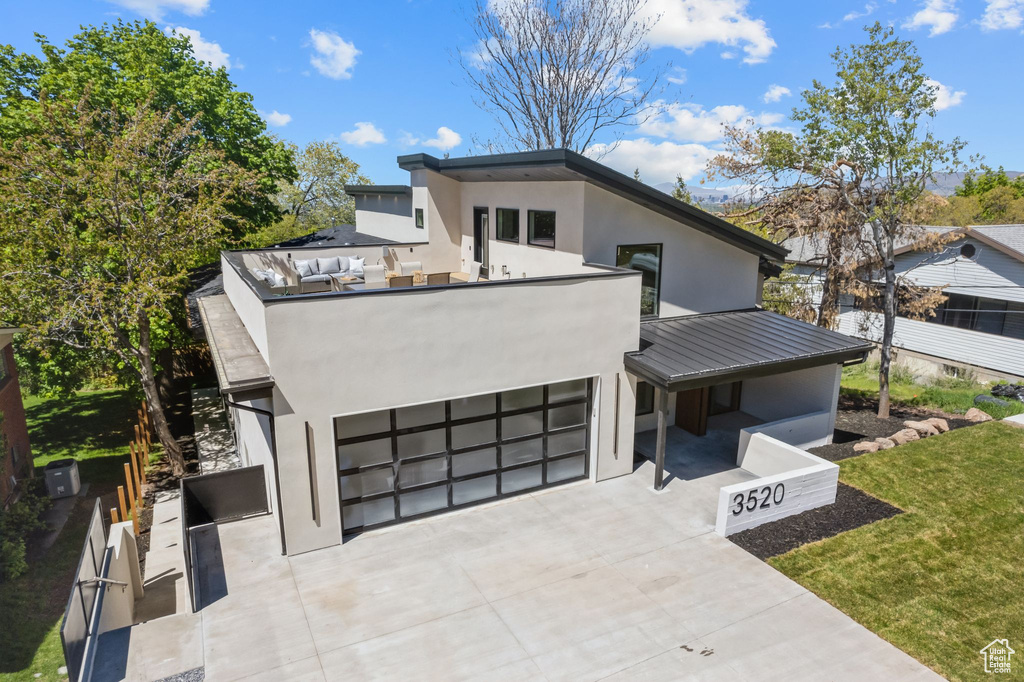 Modern home featuring concrete driveway, a standing seam roof, stucco siding, and a garage