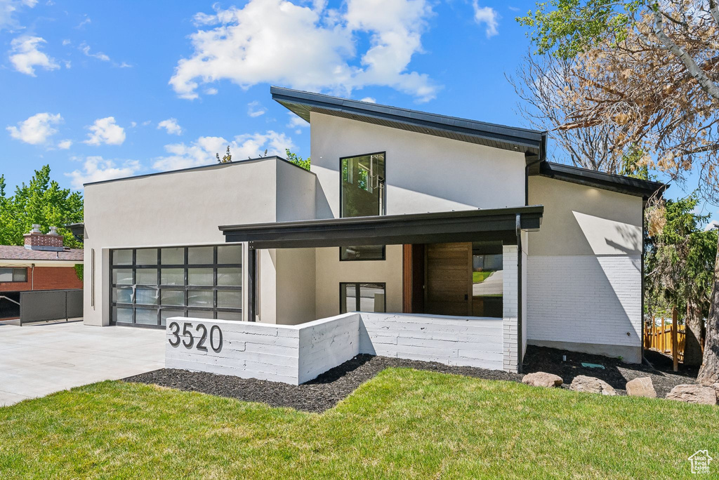 View of front of house with an attached garage, stucco siding, fence, a front lawn, and driveway