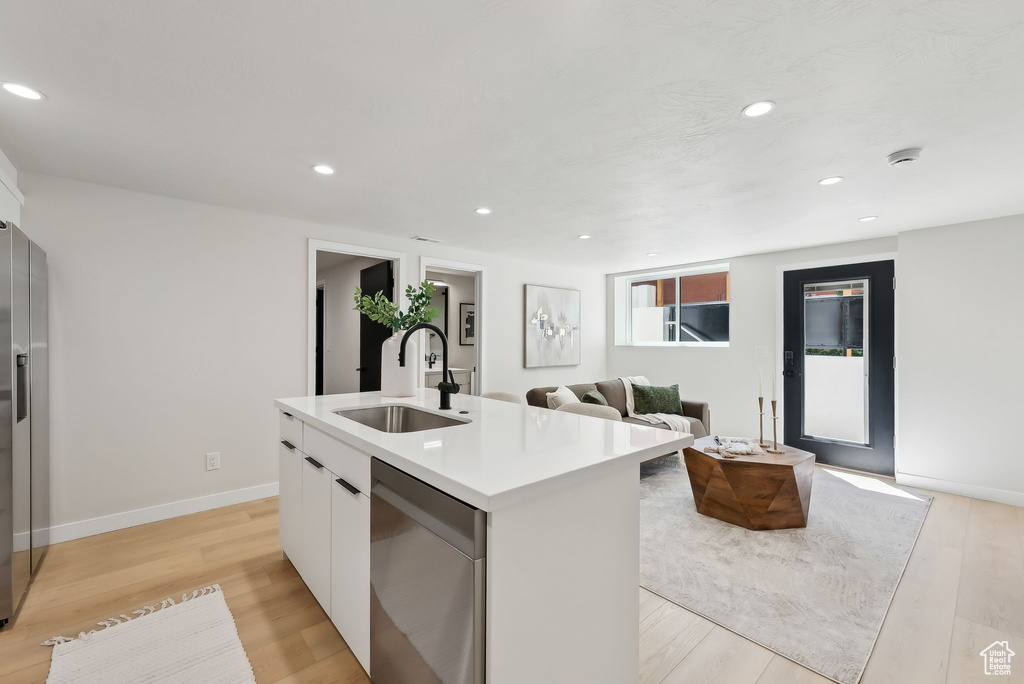 Kitchen with a sink, an island with sink, white cabinetry, stainless steel dishwasher, and modern cabinets