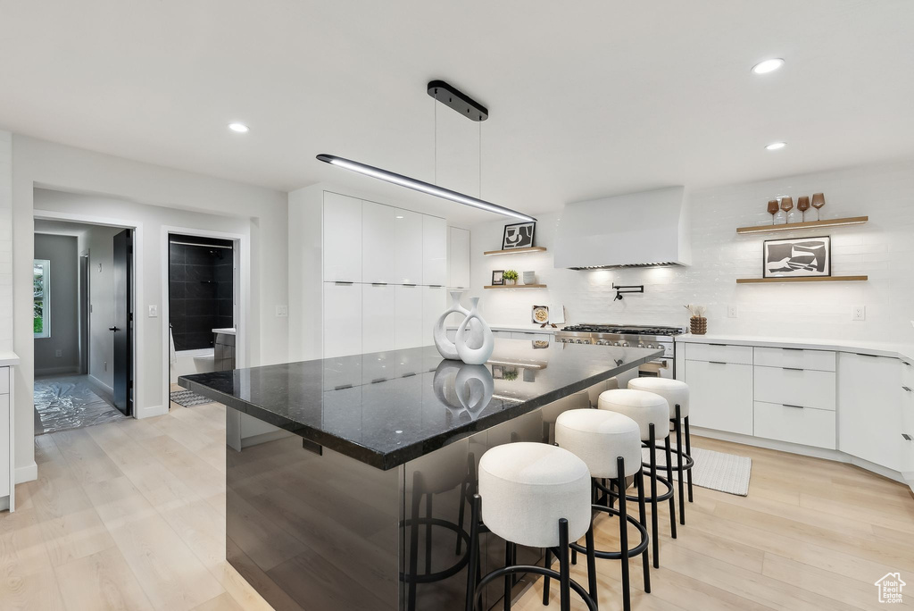 Kitchen with light wood finished floors, modern cabinets, white cabinetry, open shelves, and a kitchen island