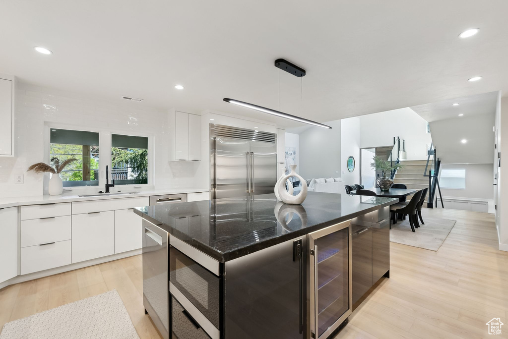 Kitchen featuring a sink, white cabinetry, built in appliances, modern cabinets, and wine cooler