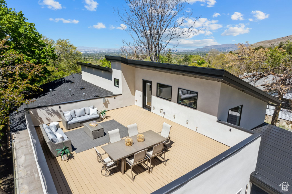 Rear view of property featuring stucco siding, an outdoor hangout area, outdoor dining area, and a deck with mountain view