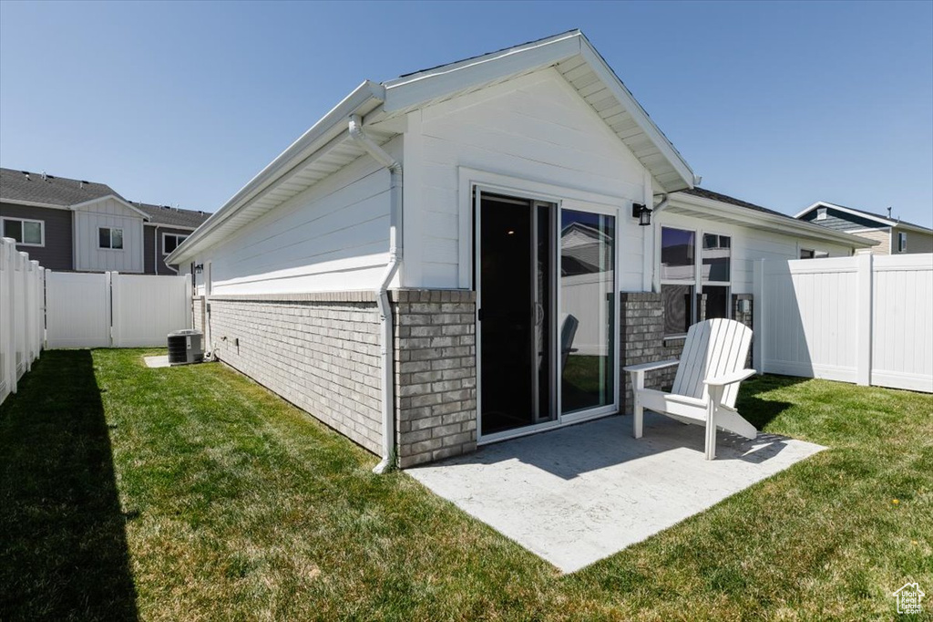 Back of house with a lawn, a fenced backyard, a patio area, and brick siding