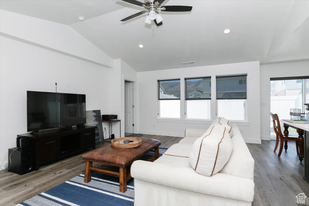 Living area with a ceiling fan, visible vents, wood finished floors, and lofted ceiling
