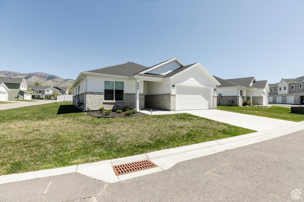 Single story home featuring a garage, concrete driveway, brick siding, and a front yard